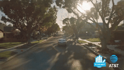A Car Is Driving Down A Street Next To A Sign That Says It Can Wait GIF