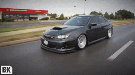A Car Is Driving Down A Street With A Bk Logo On The Bottom Right GIF