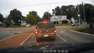 A Car Is Driving Down A Street With A Sign That Says Williams Plaza GIF