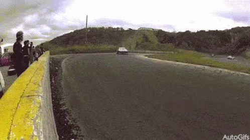 A Car Is Driving Down A Track With A Yellow Barrier . GIF