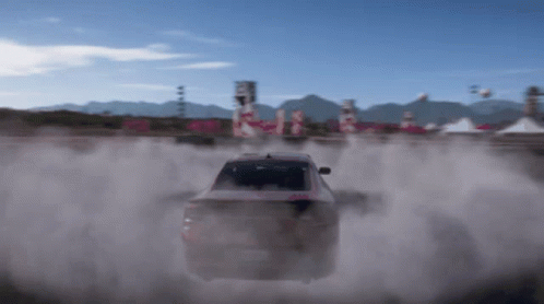 A Car Is Driving On A Dirt Road With Smoke Coming Out Of The Back GIF