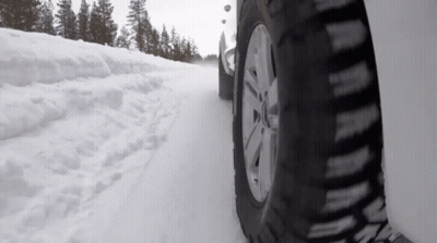 A Car Is Driving On A Snow Covered Road GIF