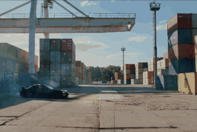 A Car Is Driving Through A Warehouse With Containers Stacked On Top Of Each Other And One Of The Containers Says Aa GIF