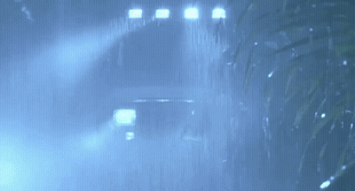 A Car Is Driving Through The Rain In The Dark . GIF