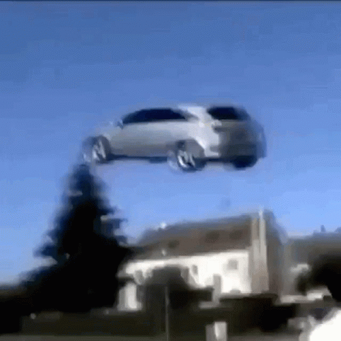 A Car Is Flying Through A Blue Sky Over A House GIF