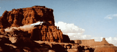 A Car Is Flying Through The Air On Top Of A Rocky Cliff GIF