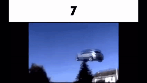 A Car Is Flying Through The Air While Sitting On Top Of A Building . GIF