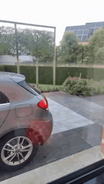 A Car Is Parked In A Driveway Next To A Fence GIF