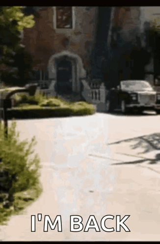 A Car Is Parked In Front Of A House With The Words I 'M Back Written On The Sidewalk . GIF