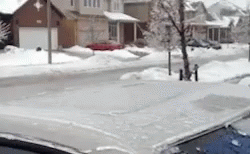 A Car Is Parked On The Side Of The Road In Front Of A Snow Covered Street . GIF