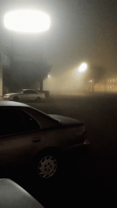 A Car Parked In A Foggy Parking Lot At Night GIF
