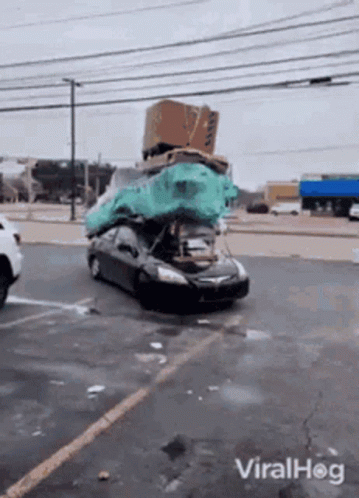 A Car With A Bunch Of Boxes On Top Of It In A Parking Lot GIF