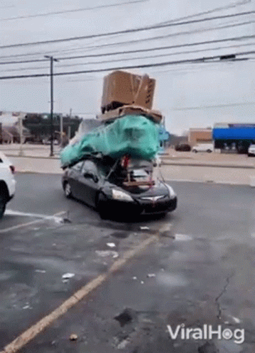 A Car With A Bunch Of Boxes On Top Of It Is Driving Down The Street . GIF