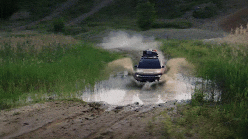 A Car With A Roof Rack Is Driving Through A Puddle GIF
