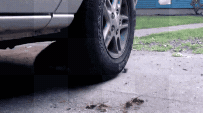 A Car With A Tire That Says Bfgoodrich On It Is Parked On The Sidewalk . GIF