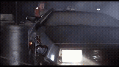 A Car With The Headlights On Is Driving Down A Dark Street GIF