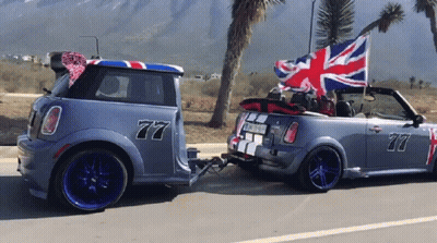 A Car With The Number 77 On The Side Is Pulling Another Car GIF