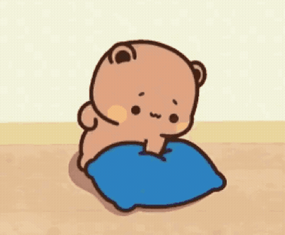 A Cartoon Bear Is Sitting On A Blue Pillow On A Wooden Floor . GIF