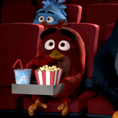 A Cartoon Bird Is Sitting In A Theater Holding A Tray Of Popcorn GIF