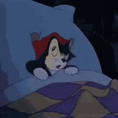 A Cartoon Cat Is Laying In A Bed With A Pillow . GIF