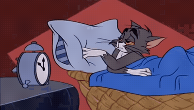 A Cartoon Cat Is Sleeping In A Bed Next To An Alarm Clock GIF