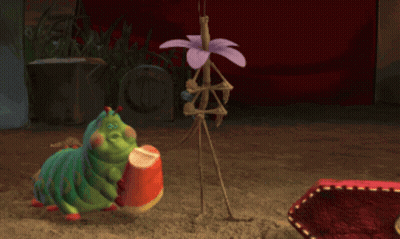 A Cartoon Caterpillar Is Holding A Candy Corn In Its Hand GIF