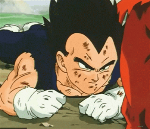 A Cartoon Character From Dragon Ball Z Is Laying On The Ground With His Fist In The Air . GIF