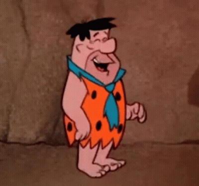 A Cartoon Character From The Flintstones Is Standing In Front Of A Rock Wall . GIF