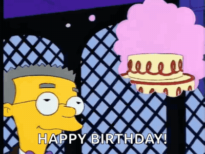 A Cartoon Character From The Simpsons Is Standing Next To A Cake With A Pink Wig . GIF