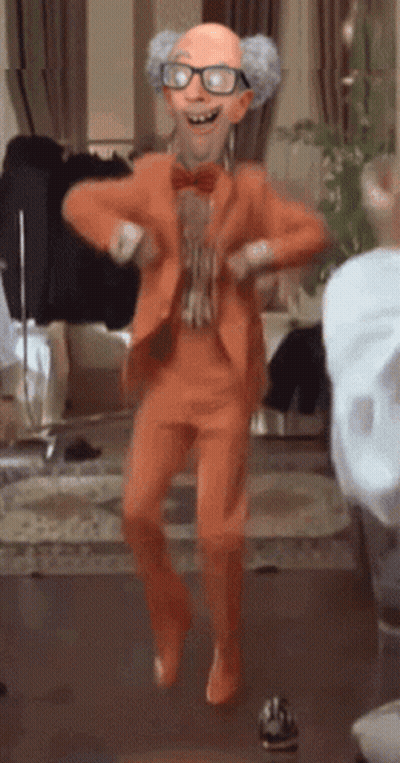 A Cartoon Character In An Orange Suit Is Dancing In A Room GIF