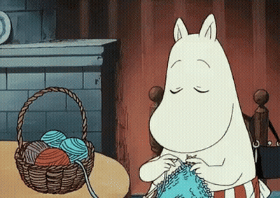 A Cartoon Character Is Knitting A Sweater In Front Of A Basket Of Yarn . GIF