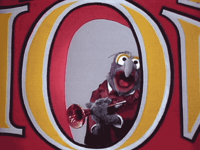 A Cartoon Character Is Playing A Trumpet In Front Of A Large Letter O GIF