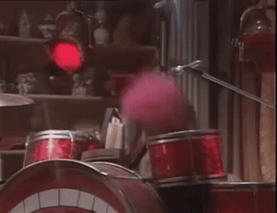 A Cartoon Character Is Playing Drums In A Room With A Red Light Behind Them . GIF