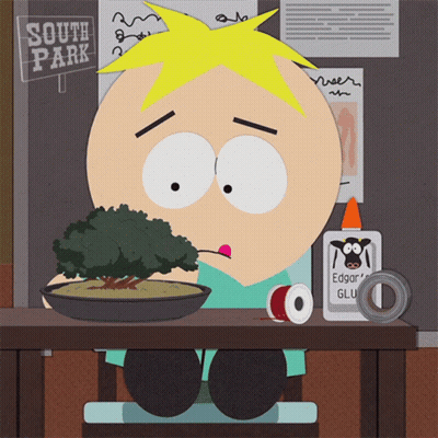 A Cartoon Character Is Sitting At A Table With A Sign That Says South Park In The Background GIF