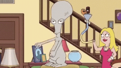 A Cartoon Character Is Sitting On A Couch In A Living Room Next To A Staircase . GIF
