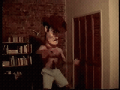 A Cartoon Character Is Standing In A Room With A Brick Wall . GIF