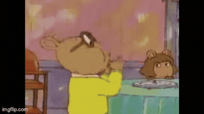 A Cartoon Character Is Standing In Front Of A Table With A Plate Of Food On It . GIF