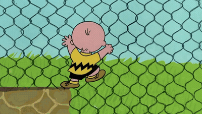 A Cartoon Character Named Charlie Brown Stands Behind A Chain Link Fence GIF