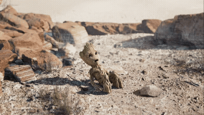 A Cartoon Character Named Groot Is Sitting On The Ground In The Desert GIF