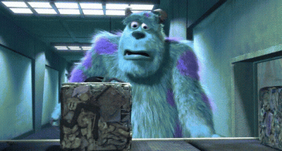 A Cartoon Character Named Sulley Is Standing In A Hallway Looking At A Box GIF