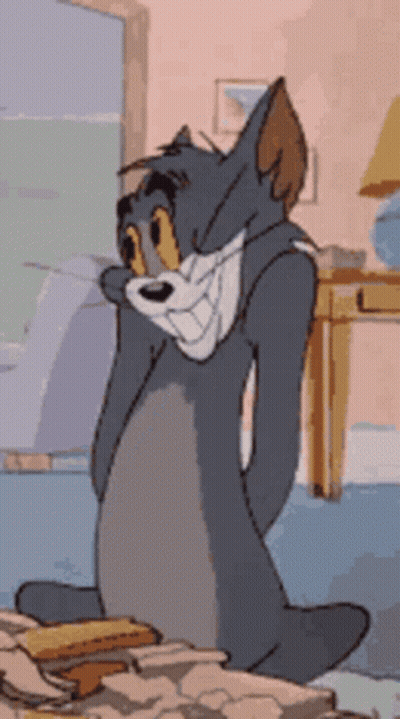 A Cartoon Character Named Tom Is Sitting On A Bed GIF