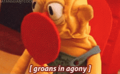 A Cartoon Character Says Groans In Agony While Holding A Red Object In Its Mouth GIF