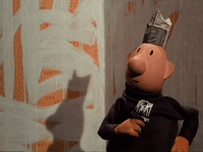 A Cartoon Character Wearing A Newspaper Hat Is Standing In Front Of A Wall With A Shadow Of A Cat On It GIF