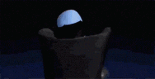 A Cartoon Character With A Large Head Is Sitting In A Chair With His Hands Folded . GIF