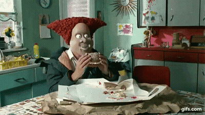 A Cartoon Character With A Red Hat Is Eating A Sandwich In A Kitchen . GIF