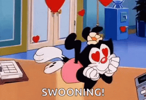 A Cartoon Character With Hearts In Her Eyes Is Sitting On A Desk With Balloons In The Background . GIF