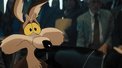 A Cartoon Coyote With Big Yellow Eyes Looks At The Camera GIF