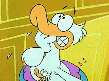 A Cartoon Duck With An Orange Beak Is Sitting On A Pillow GIF