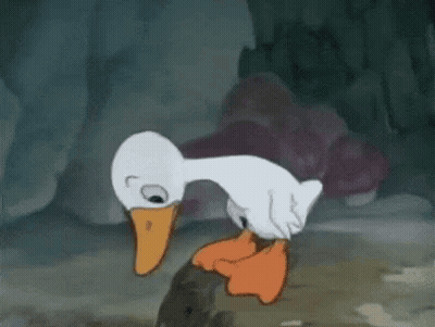 A Cartoon Duck With An Orange Beak Is Standing Next To A Rock . GIF