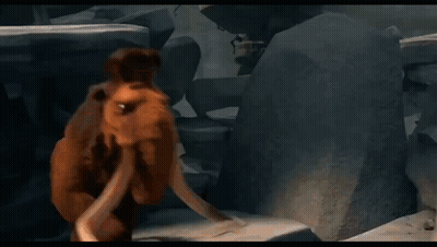 A Cartoon Elephant With Long Tusks Is Standing In Front Of A Rock Wall . GIF